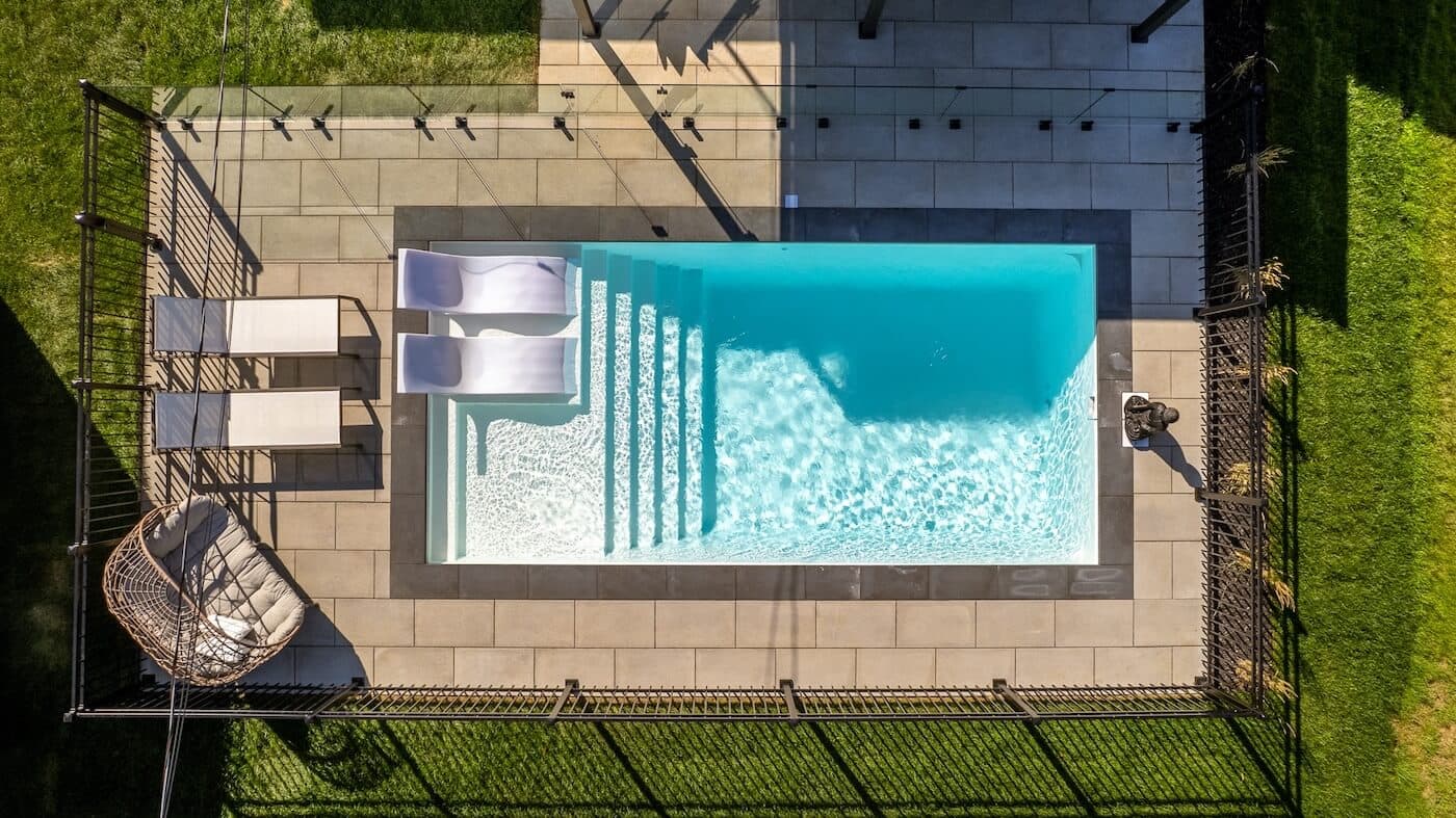 Modern backyard fiberglass pool with lounge chairs